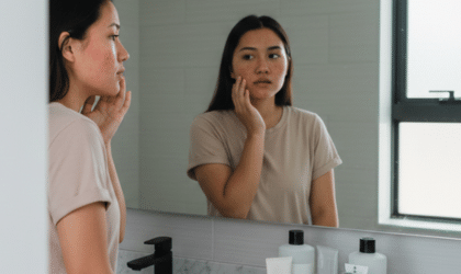 The Hidden Signs Your Skincare Products Are Damaging Your Skin, Not Helping It 9 Woman checking irritated skin in mirror as skincare products are damaging your skin